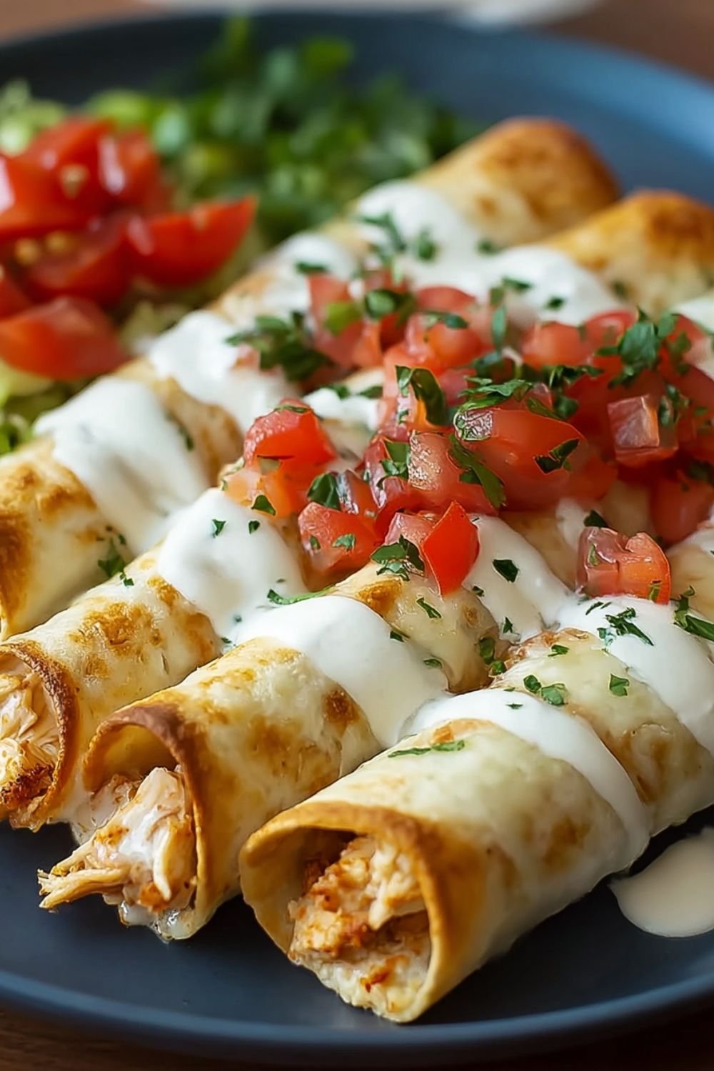 Baked cream cheese chicken taquitos on white platter with sour cream and salsa