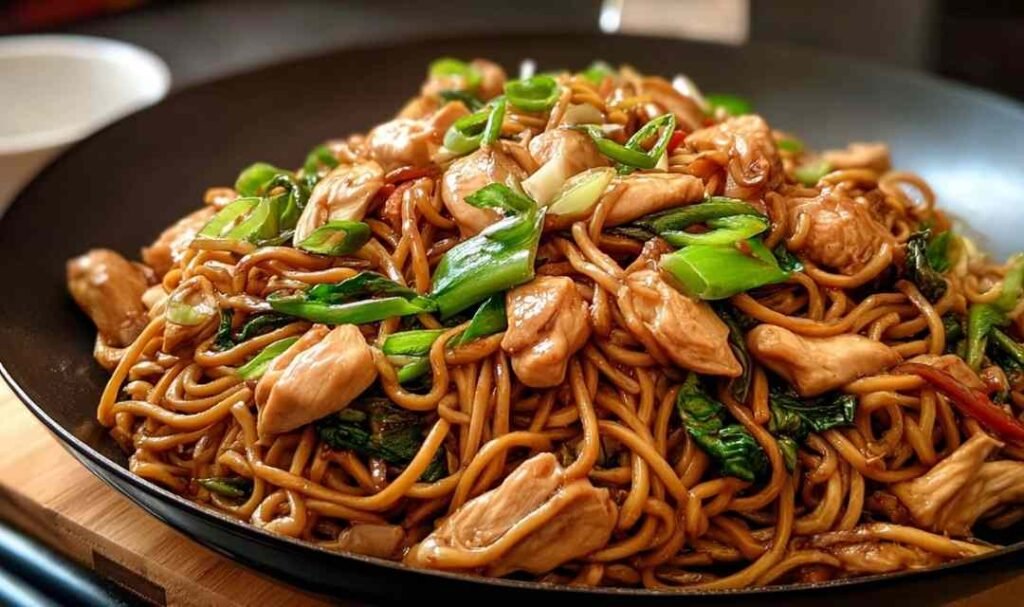 Chicken lo mein recipe with golden chicken strips and colorful vegetables in skillet