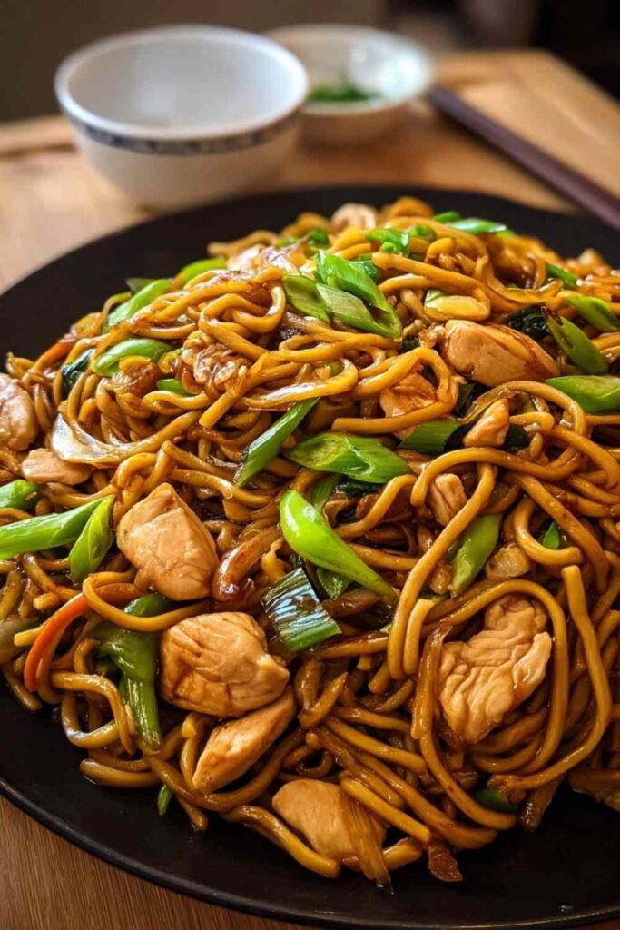Chicken lo mein recipe with golden chicken strips and colorful vegetables in skillet