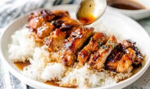 Easy chicken teriyaki sliced and glazed with homemade teriyaki sauce served over steamed white rice with sesame seeds