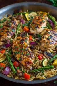 Easy balsamic chicken and veggie orzo in skillet with golden chicken and colorful vegetables