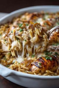 French onion chicken orzo casserole in skillet with melted cheese topping fresh from oven SEO Filename: french-onion-chicken-orzo-casserole-baked-cheese