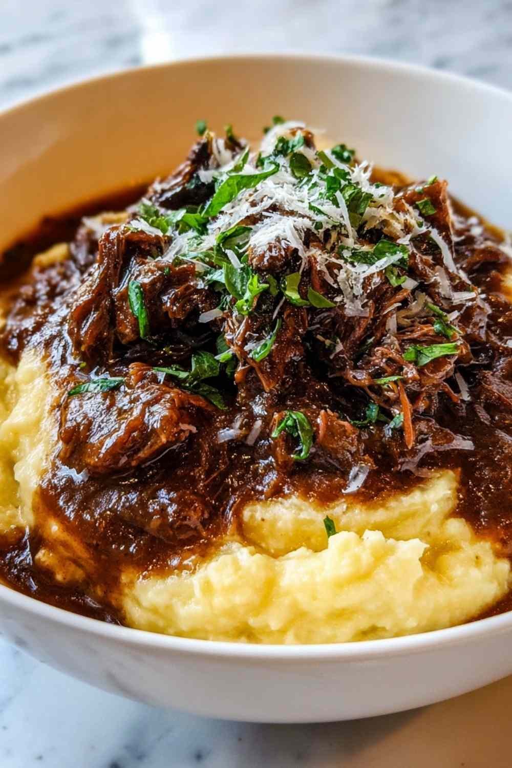 Short Rib Ragu with Parmesan Mashed Potatoes served on a white plate garnished with fresh parsley