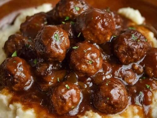 Slow Cooker Salisbury Chicken Meatballs in a crockpot with thick savory onion-brown gravy and fresh parsley garnish
