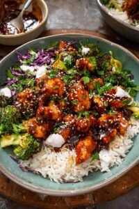 sticky chicken bowls with glazed chicken rice broccoli and spicy mayo drizzle topped with sesame seeds