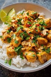 Thai peanut chicken pieces coated in creamy sauce in a large skillet ready to serve