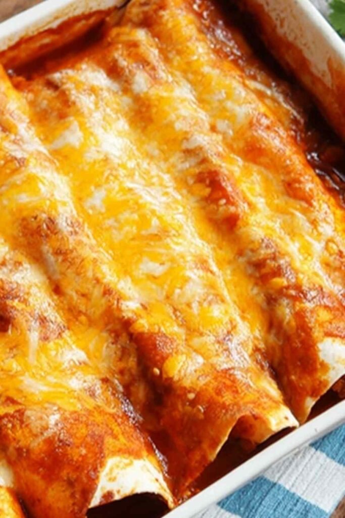 A baking dish of 5 Ingredient Beef Enchiladas covered in melted cheese and red enchilada sauce, fresh from the oven