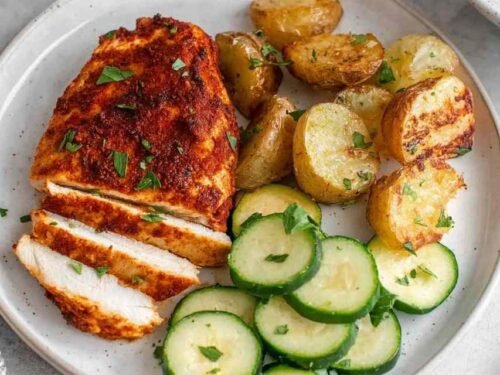 Juicy sliced air fryer chicken breast on a white plate with a golden spice crust