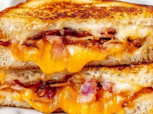 Bacon grilled cheese sandwich cut in half showing layers of melted cheddar, Monterey Jack, and crispy bacon on golden sourdough bread