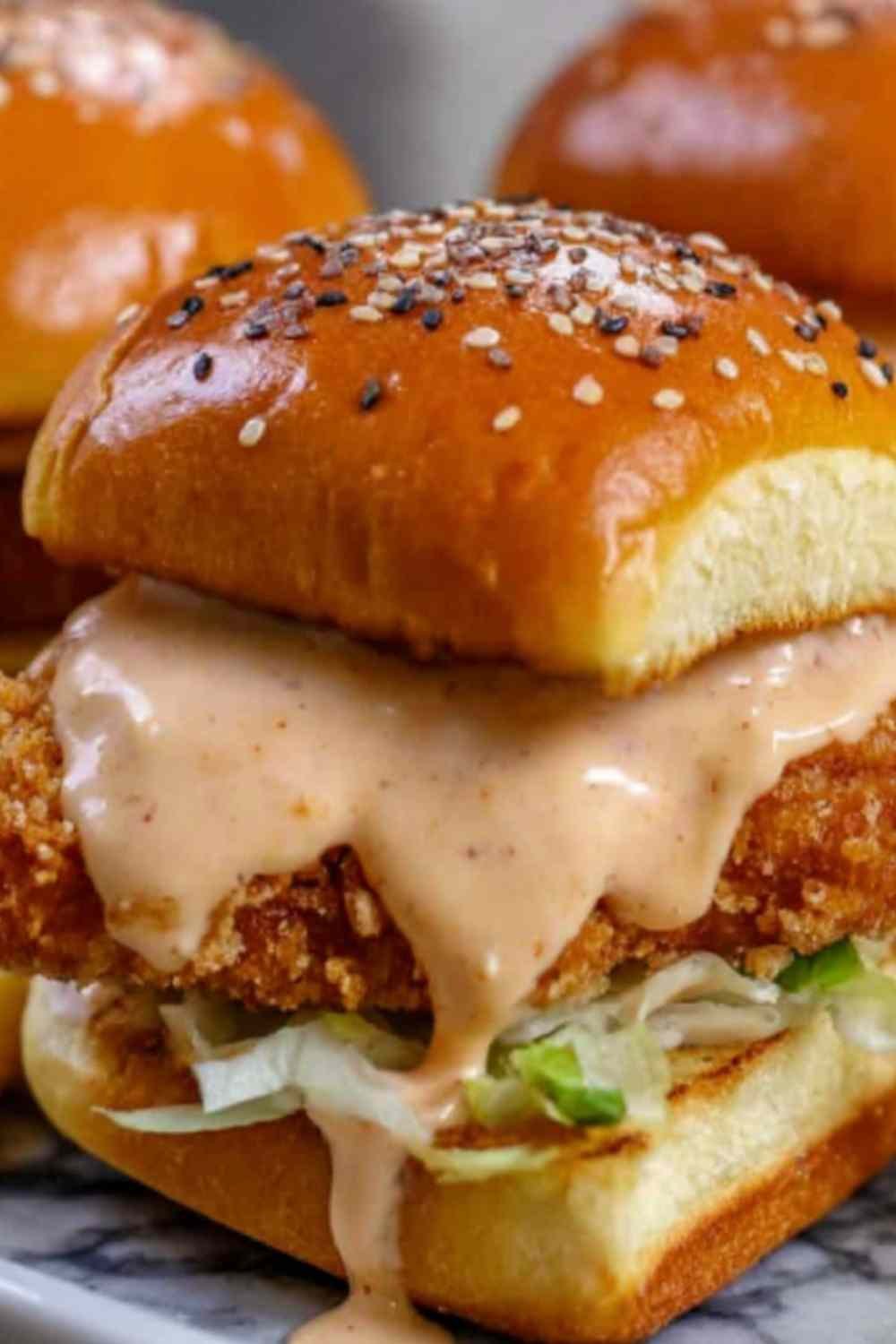 Bang Bang Chicken Sliders with creamy spicy sauce, fresh lettuce, and tomato on fluffy mini buns