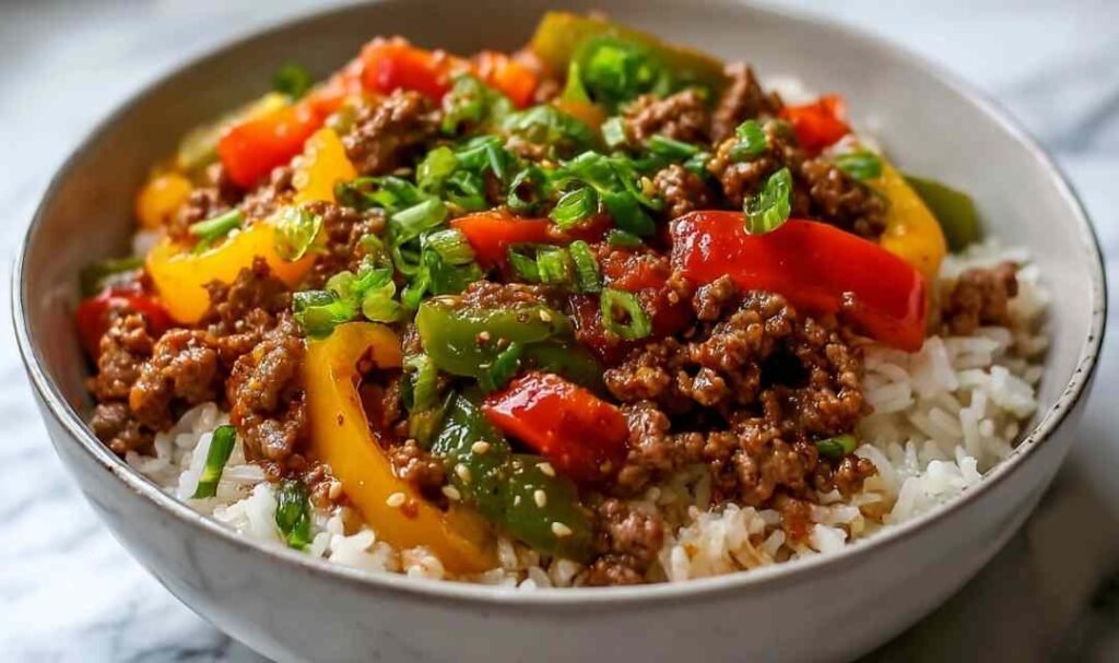 Beef pepper rice bowl in a large skillet with seasoned ground beef, colorful bell peppers, and jasmine rice
