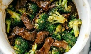 Beef and broccoli stir fry in a cast iron skillet with thick savory sauce and sesame seed garnish