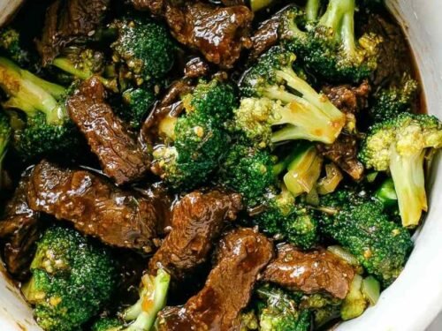 Beef and broccoli stir fry in a cast iron skillet with thick savory sauce and sesame seed garnish