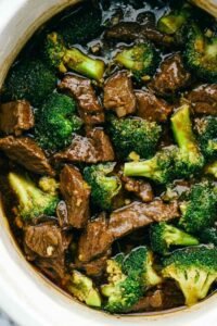 Beef and broccoli stir fry in a cast iron skillet with thick savory sauce and sesame seed garnish
