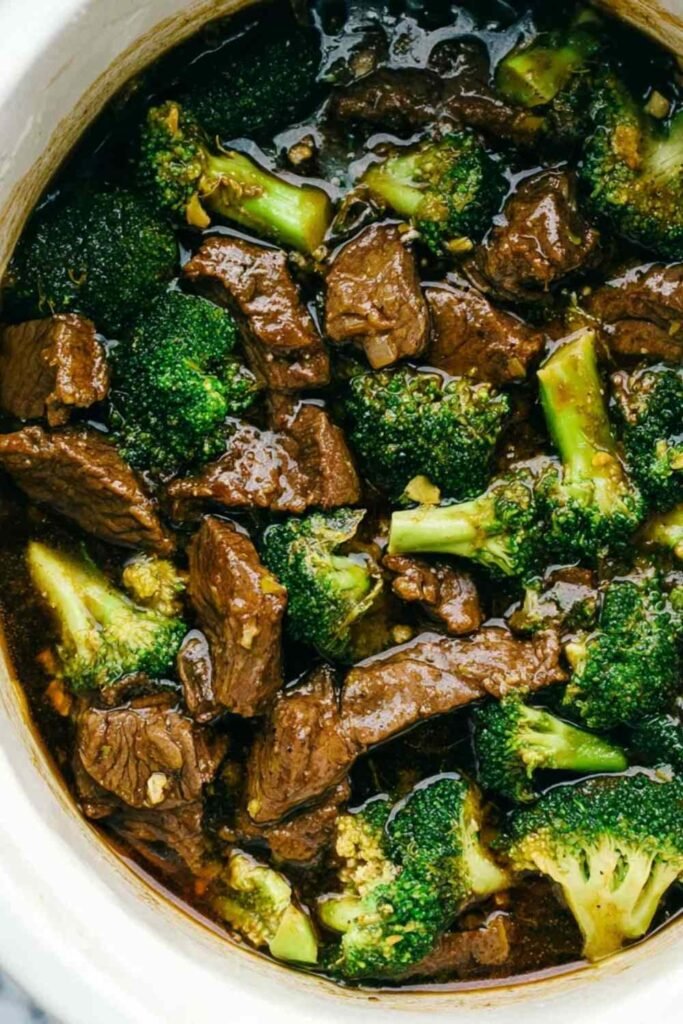 Beef and broccoli stir fry in a cast iron skillet with thick savory sauce and sesame seed garnish