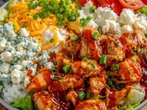 Buffalo chicken protein bowl with rice, lettuce, cherry tomatoes, cheddar, and ranch drizzle