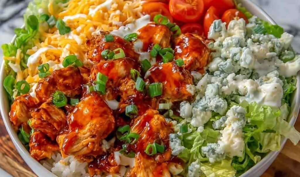Buffalo chicken protein bowl with fluffy rice shredded cheddar cherry tomatoes and ranch drizzle