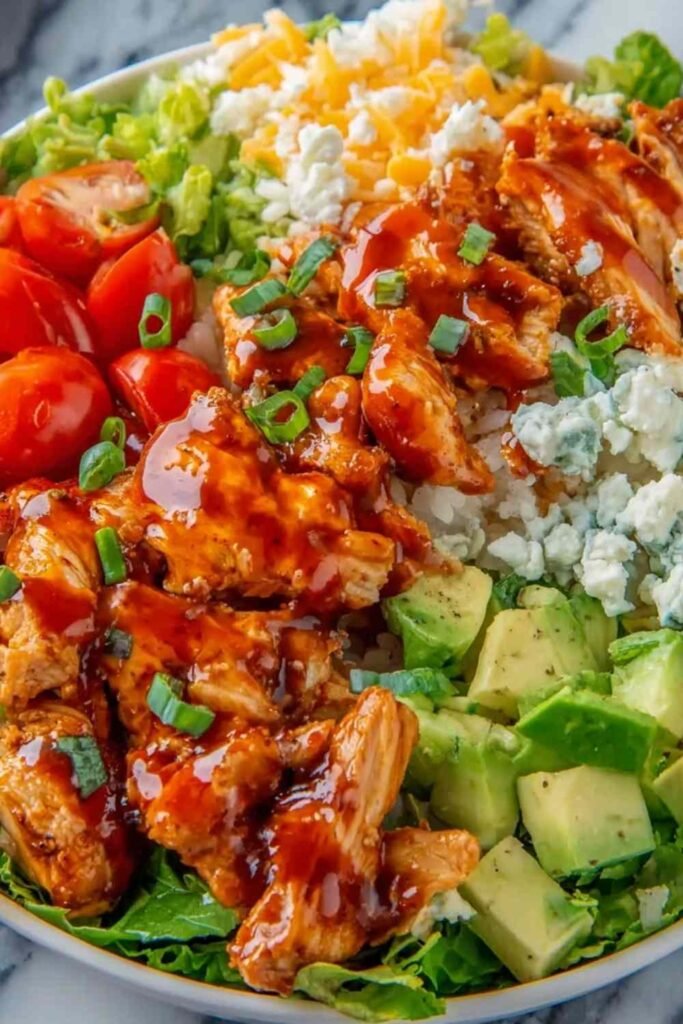 Buffalo chicken protein bowl with fluffy rice shredded cheddar cherry tomatoes and ranch drizzle