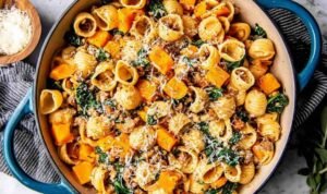 Skillet of butternut squash pasta with Italian sausage, spinach, and Parmesan