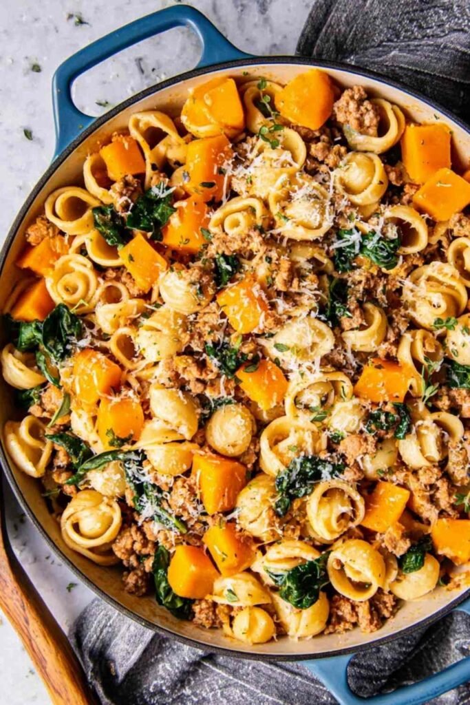 Skillet of butternut squash pasta with Italian sausage, spinach, and Parmesan