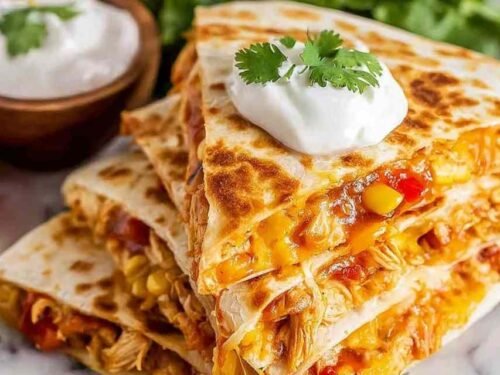 Golden crispy chicken quesadilla slices served with guacamole and salsa on a white plate
