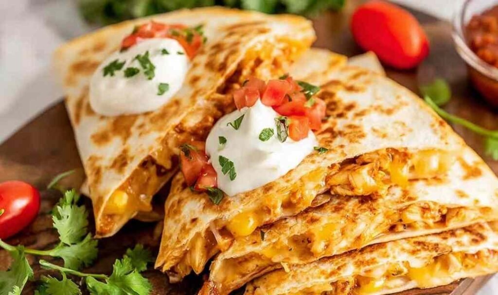 Golden crispy chicken quesadilla slices served with guacamole and salsa on a white plate
