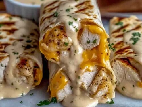 Cheesy Garlic Chicken Wraps sliced diagonally on a white plate showing melted cheese and seasoned chicken filling