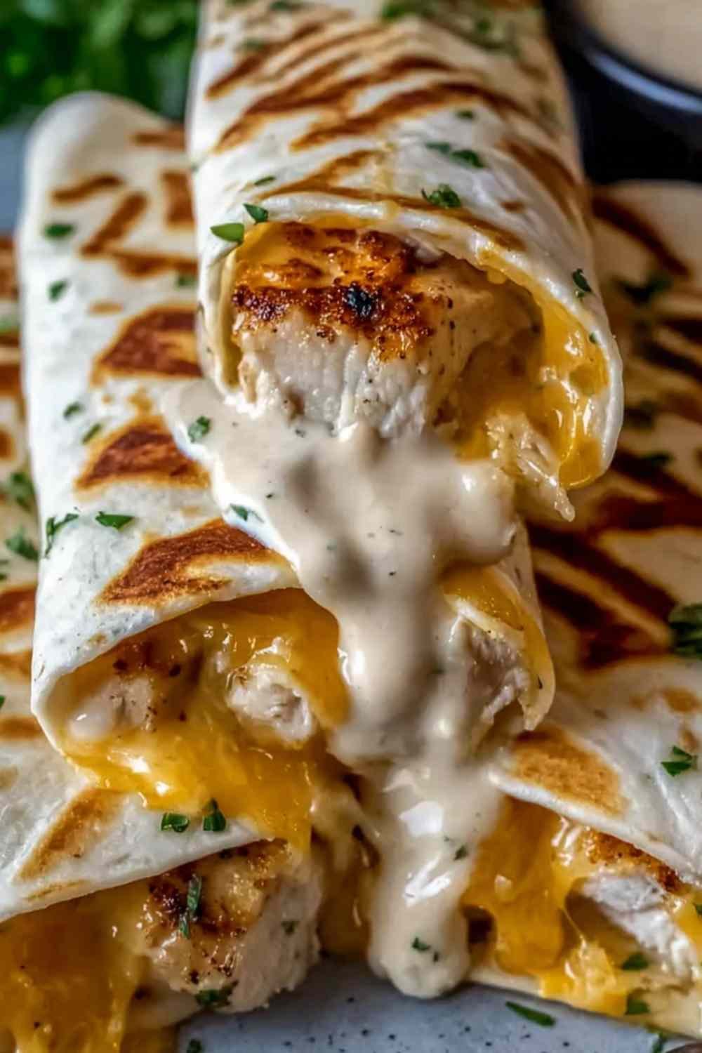 Cheesy Garlic Chicken Wraps sliced diagonally on a white plate showing melted cheese and seasoned chicken filling