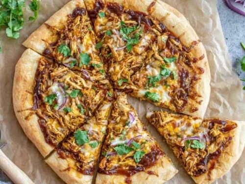 Freshly baked BBQ chicken pizza with shredded chicken, smoked Gouda, mozzarella, red onion, and cilantro on a golden crispy crust