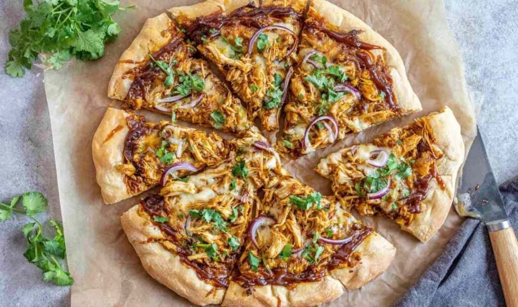 Freshly baked BBQ chicken pizza with shredded chicken, smoked Gouda, mozzarella, red onion, and cilantro on a golden crispy crust