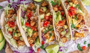 Easy Chicken Tacos Overhead view of chicken tacos filled with seasoned chopped chicken, shredded lettuce, tomato, red onion, and avocado in flour tortillas
