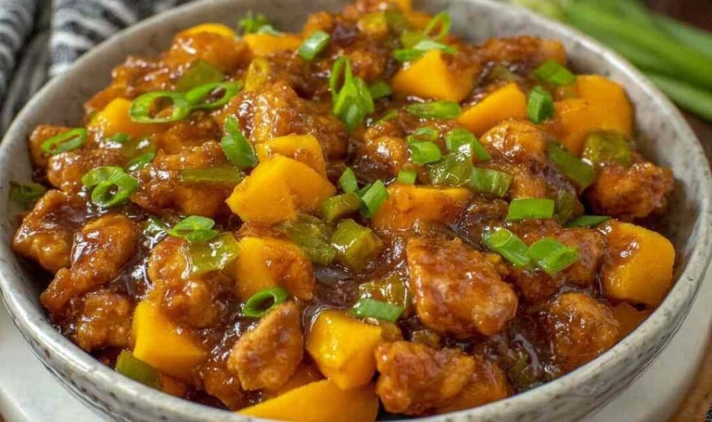 Chinese Style Mango Chicken Stir Fry with crispy golden chicken and mango in glossy savory-sweet sauce in a wok