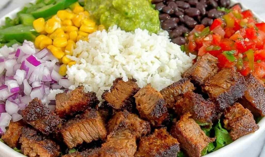 Copycat Chipotle steak cubes caramelizing in a cast iron skillet with smoky chipotle adobo marinade