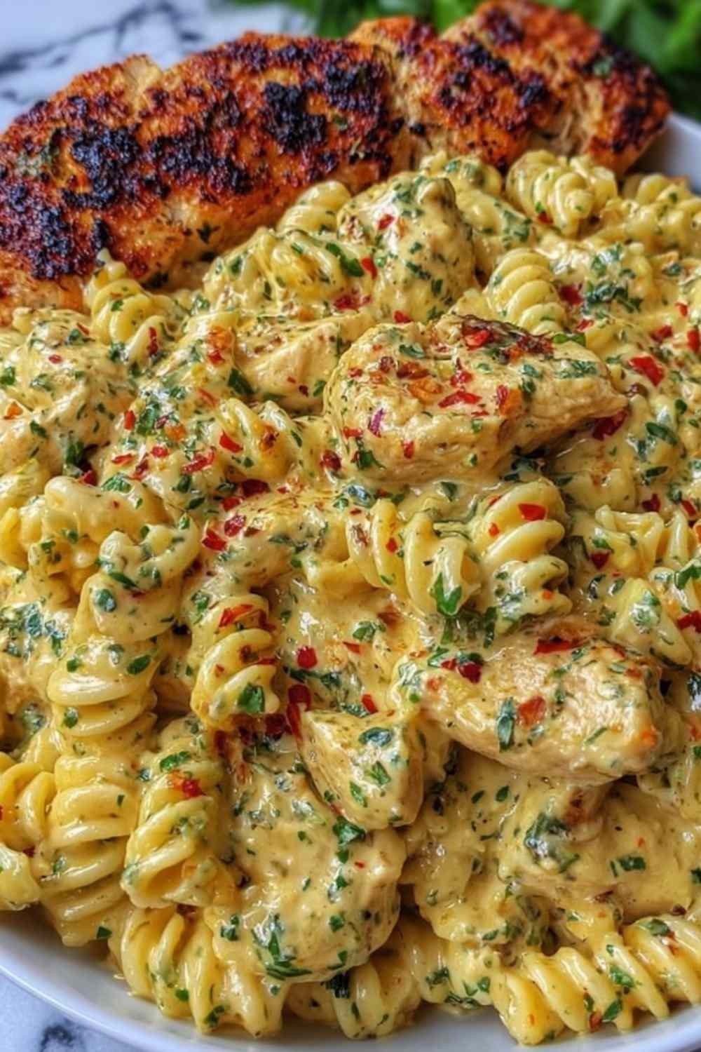 Creamy garlic Parmesan chicken pasta in a large skillet garnished with fresh parsley and grated Parmesan