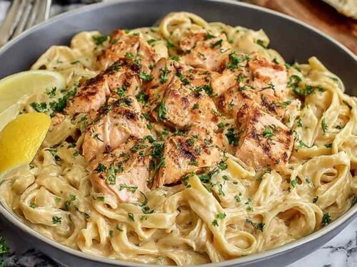 A bowl of creamy salmon pasta with fettuccine, flaked salmon, and fresh dill in a lemon parmesan cream sauce