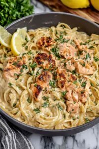 A bowl of creamy salmon pasta with fettuccine, flaked salmon, and fresh dill in a lemon parmesan cream sauce
