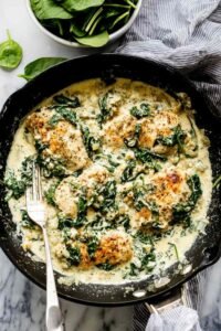 Creamy spinach chicken in a skillet with golden chicken cutlets and wilted spinach in garlic cream sauce