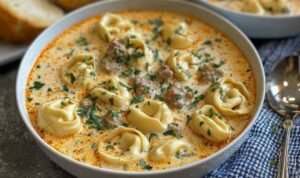 Creamy Tortellini Soup in a Dutch oven with cheese tortellini, Italian sausage, kale, and creamy tomato broth