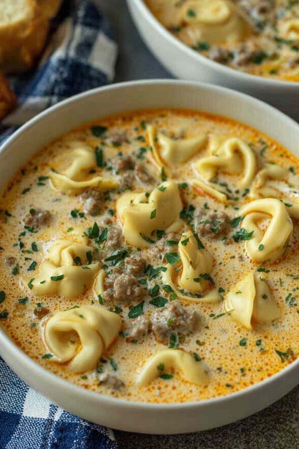 Creamy Tortellini Soup in a Dutch oven with cheese tortellini, Italian sausage, kale, and creamy tomato broth