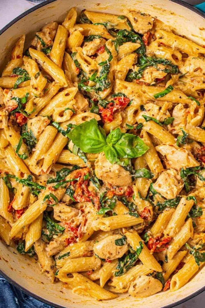 One pot tuscan chicken pasta with sun-dried tomatoes, spinach, and creamy Parmesan sauce in a large deep skillet