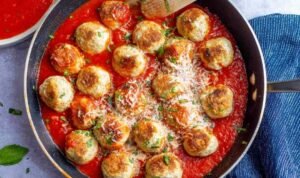 Chicken parmesan meatballs served over spaghetti with marinara sauce and freshly grated Parmesan cheese