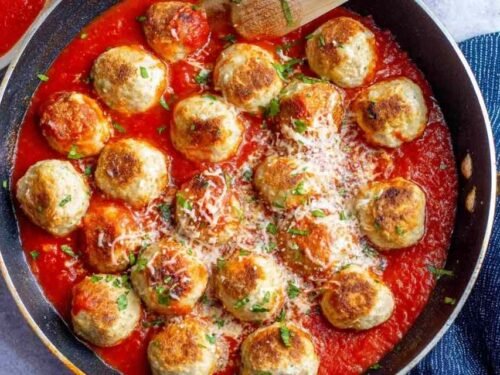 Chicken parmesan meatballs served over spaghetti with marinara sauce and freshly grated Parmesan cheese