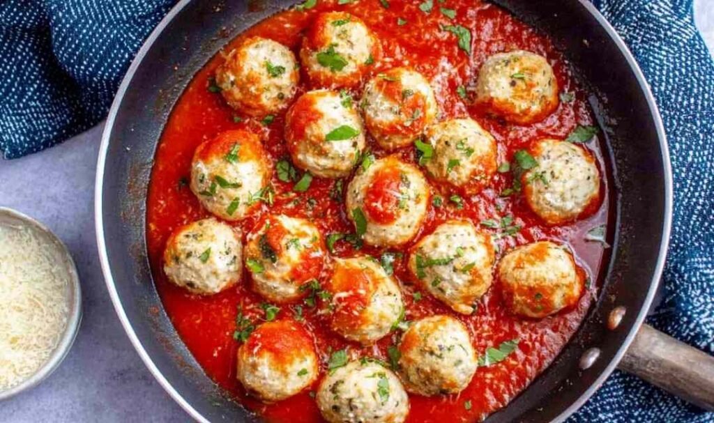 Chicken parmesan meatballs served over spaghetti with marinara sauce and freshly grated Parmesan cheese