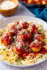 Chicken parmesan meatballs served over spaghetti with marinara sauce and freshly grated Parmesan cheese