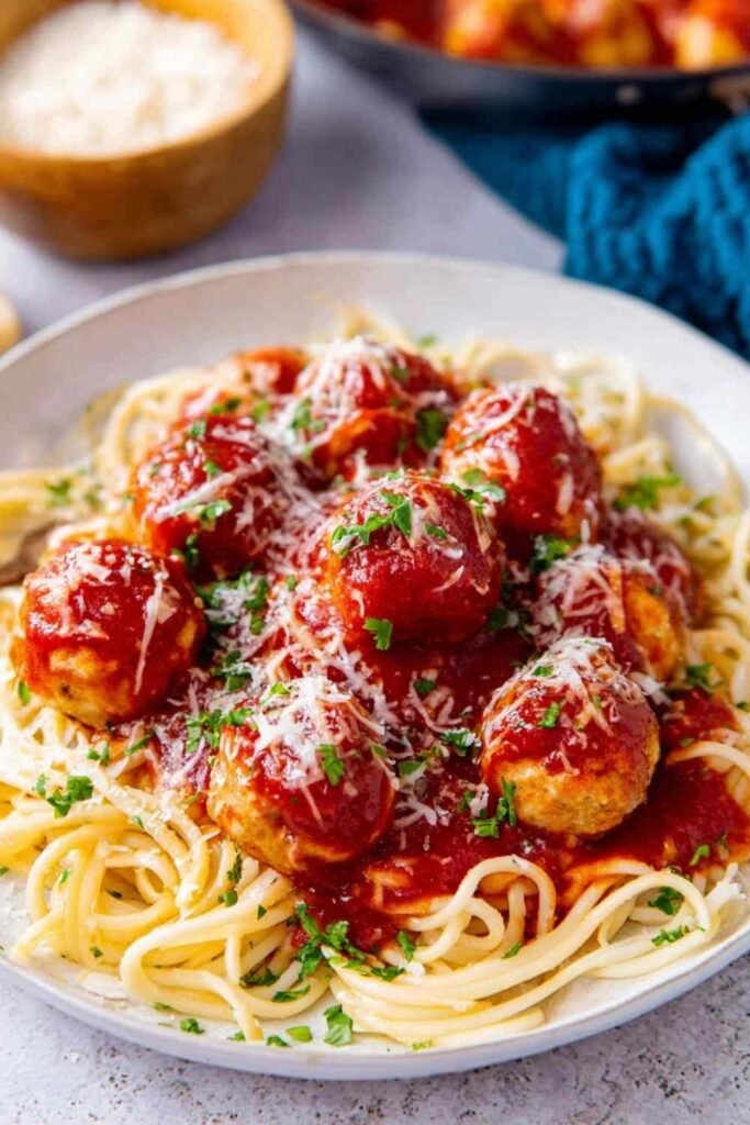 Chicken parmesan meatballs served over spaghetti with marinara sauce and freshly grated Parmesan cheese