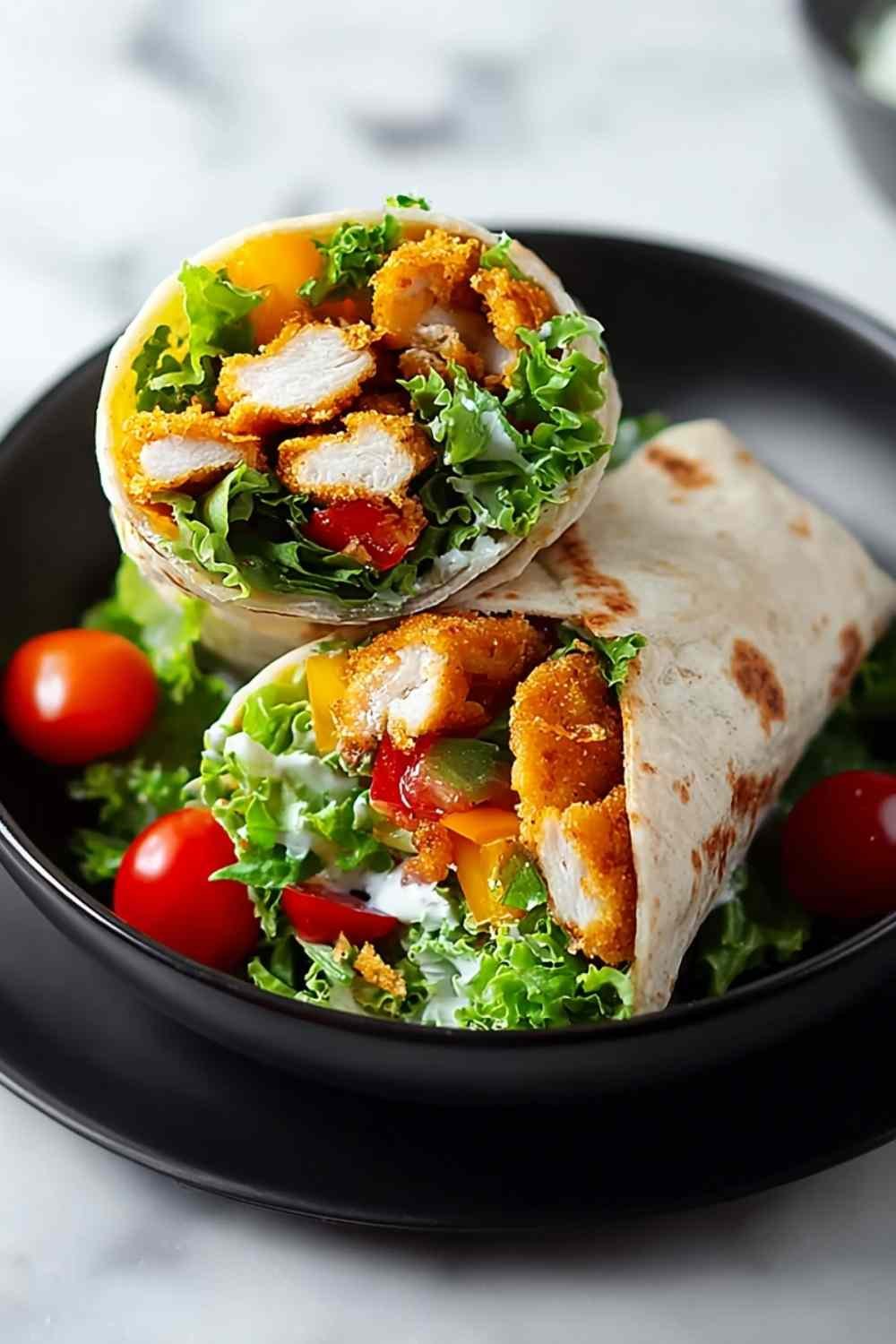Crispy chicken ranch snack wrap cut in half showing golden breaded chicken, cheddar, shredded lettuce, and creamy ranch inside a flour tortilla