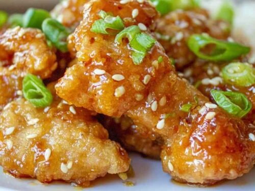 Crispy Chinese honey garlic chicken served over white rice with sesame seeds and sliced green onions