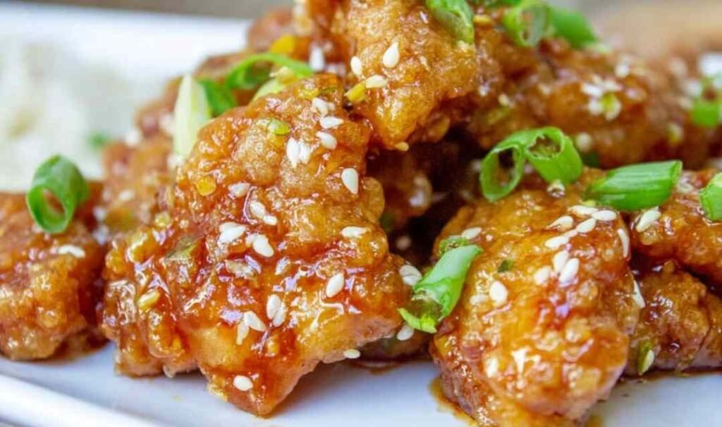Crispy Chinese honey garlic chicken served over white rice with sesame seeds and sliced green onions