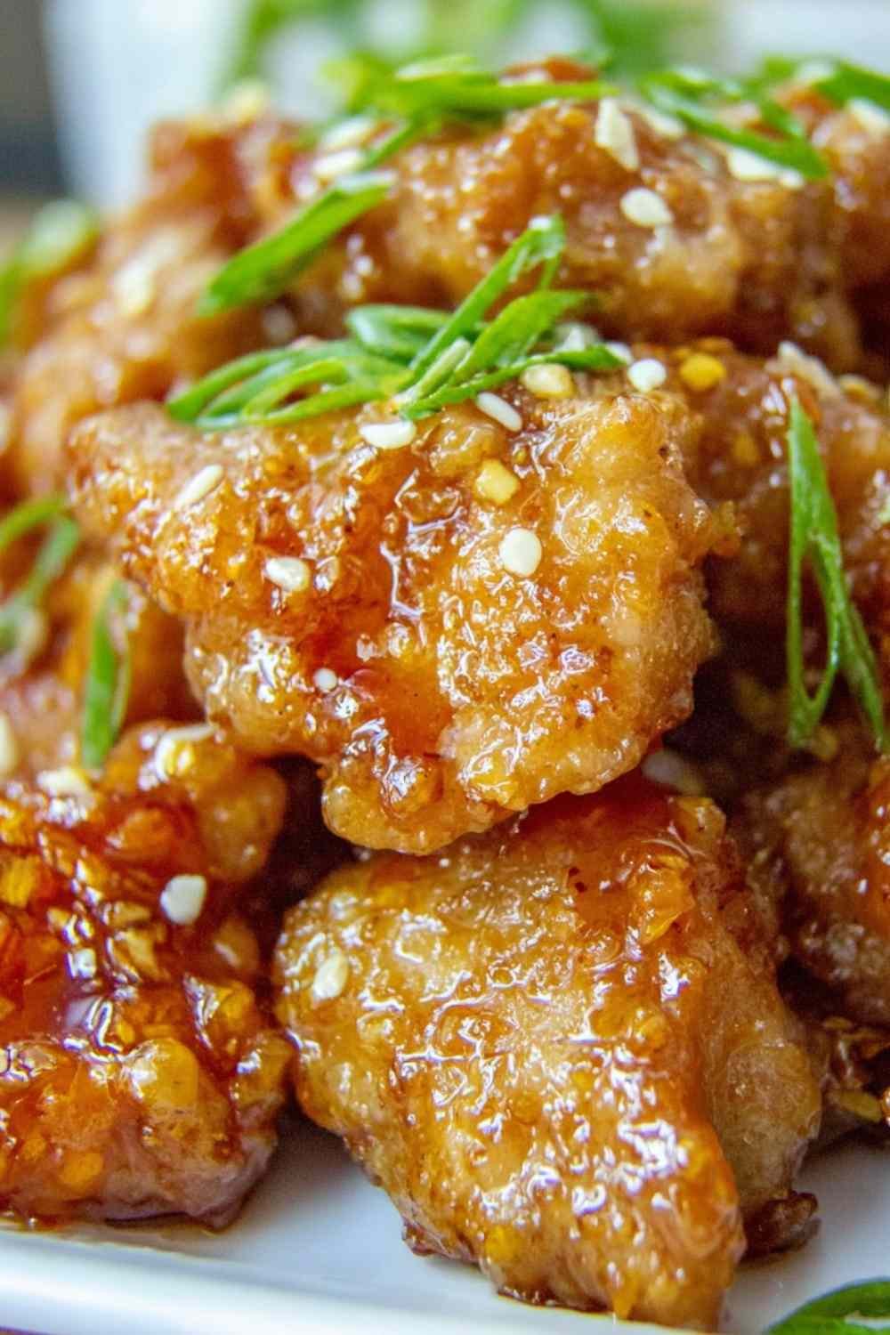 Crispy Chinese honey garlic chicken served over white rice with sesame seeds and sliced green onions