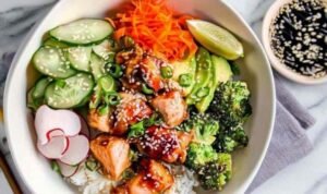 Crispy salmon bowls with glazed soy honey salmon, sushi rice, avocado, cucumber, and sesame seeds in white bowls